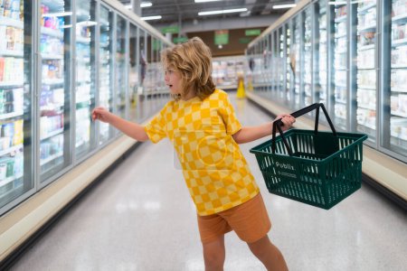 Photo for Child with shopping basket at grocery store. Funny cute child on shopping in supermarket. Grocery store. Grocery shopping, healthy lifestyle concept - Royalty Free Image