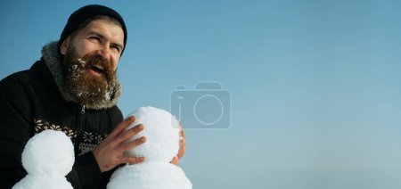 Téléchargez les photos : Gros plan portrait de l'homme faisant bonhomme de neige sur fond extérieur d'hiver. Bonhomme de neige pour bannière d'hiver - en image libre de droit