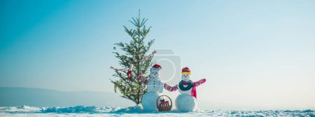Téléchargez les photos : Deux bonhomme de neige tenant la main à l'extérieur près du sapin de Noël. Bonhomme de neige sur le fond extérieur de neige. Bannière de Noël avec bonhomme de neige. Carte de voeux Nouvel An avec bonhomme de neige - en image libre de droit