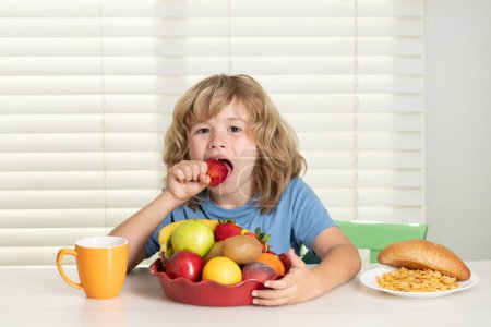 Foto de El niño come fresas, frutas orgánicas. Niño preadolescente 7, 8, 9 años comer alimentos saludables verduras - Imagen libre de derechos