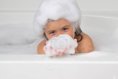 Foto de Espuma en la cabeza de los niños. Jabón sobre cabeza de niño. Niño en un baño con espuma. Procedimientos de baño e higiene infantil - Imagen libre de derechos