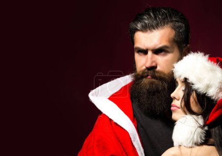 Foto de Primer retrato de pareja en sombrero de Navidad. Navidad pareja enamorada en oscuro rojo aislado estudio fondo - Imagen libre de derechos