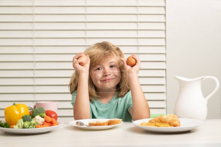 Photo for Kid eating egg. Portrait of child eat fresh healthy food in kitchen at home. Kid boy eating breakfast before school - Royalty Free Image