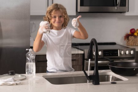 Photo for Child washing dishes with water and soap near sink in kitchen - Royalty Free Image