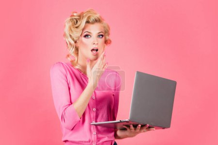 Foto de Hermosa sexy rubia pinup pop mujer de arte en rosa aislado de fondo de trabajo con el ordenador portátil - Imagen libre de derechos