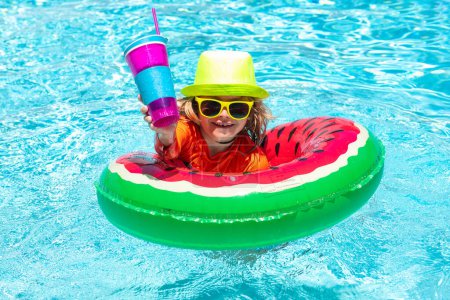 Téléchargez les photos : L'enfant nage dans l'eau de la piscine d'été. Enfant dans la piscine jouant dans l'eau. Vacances et voyages avec les enfants. Les enfants jouent à l'extérieur en été. Enfant avec anneau flottant - en image libre de droit