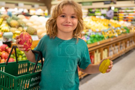 Foto de Niño con frutas. Niño eligiendo frutas y verduras durante las compras en el supermercado de verduras. Un niño yendo de compras. Comida saludable para niños - Imagen libre de derechos