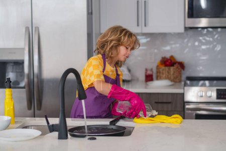 Photo for Cleaning house. Child washing dishes in the kitchen interior. Child helping his parents with housework. Too much work. Housekeeping and home cleaning concept. Child use duster and gloves for cleaning - Royalty Free Image