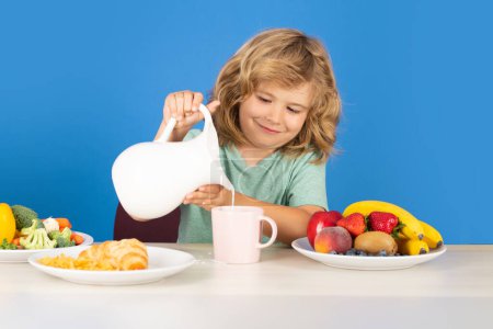 Photo for Healthy child pours milk from jug. Child drink dairy milk - Royalty Free Image