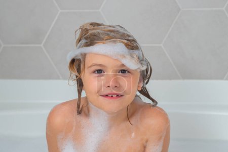 Foto de Niño con espuma de champú y burbujas en el baño de pelo. Cara divertida de niño en espuma, cuidado del cabello y concepto de higiene. Lavando cabello, champú para niños. Espuma en la cabeza del niño - Imagen libre de derechos