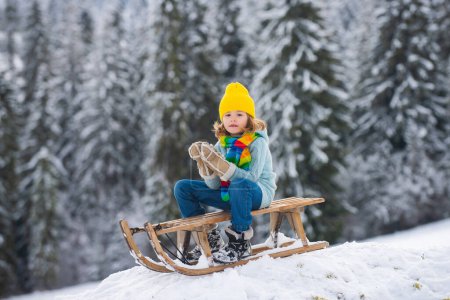Photo pour Enfants heureux s'amuser et monter le traîneau dans la forêt enneigée d'hiver, profiter de la saison d'hiver en jouant avec boule de neige - image libre de droit
