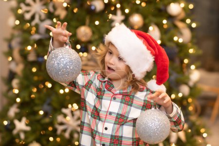 Foto de Feliz Navidad. Navidad y felices fiestas en casa. Alegre niño lindo árbol de navidad decorado. Niños con pelotas de Navidad y juguetes cerca del árbol en la habitación - Imagen libre de derechos