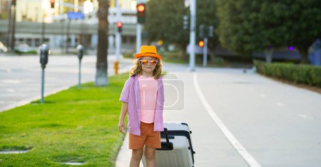Foto de Niño viajero turista en ropa de verano, sombrero. Viajar al extranjero los fines de semana. Maleta y accesorios de viajero - Imagen libre de derechos