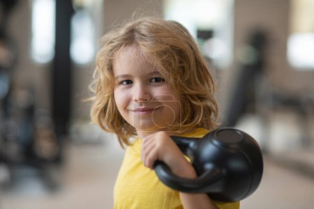 Photo for Kid workout kid in gym. Kid raising a kettlebell. Cute child training with dumbbells. Kids fitness. Kid boy exercising with dumbbells. Healthy kids - Royalty Free Image