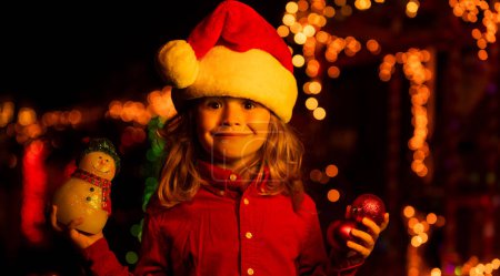Téléchargez les photos : Enfant sur la décoration de Noël devant une maison de nuit - en image libre de droit