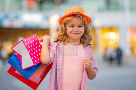 Téléchargez les photos : Enfant en shopping. Portrait d'un enfant avec des sacs à provisions. Shopping boy - en image libre de droit