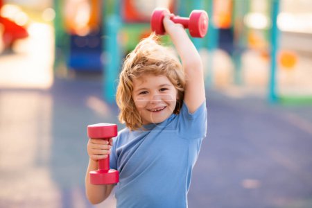 Photo for Kids sport training on playground outdoor. Child workout. Kid sport. Child exercising with dumbbells. Sporty child with dumbbell - Royalty Free Image