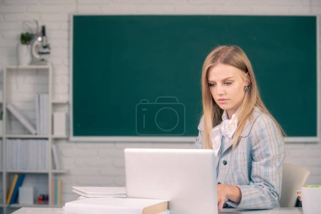 Photo for Female student in university, school education, Young woman study, sitting at table and writing on notebook in college classroom - Royalty Free Image