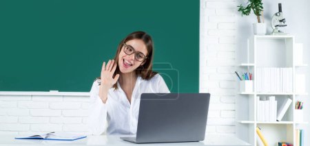 Foto de Retrato de una joven, segura y atractiva estudiante con computadora portátil en el aula de la escuela. Aprendizaje en línea en la escuela, educación a distancia - Imagen libre de derechos