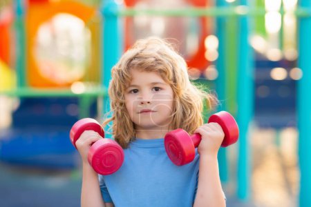 Photo for Summer sport, kids sport training on playground. Sport activities at leisure with children. Blonde boy holding dumbbells. Sports exercises for children. Funny child lifting the dumbbells - Royalty Free Image