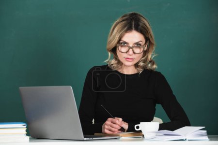 Foto de Retrato de una seria línea de enseñanza femenina concentrada de estudiantes de secundaria con computadora portátil en el aula en pizarra - Imagen libre de derechos