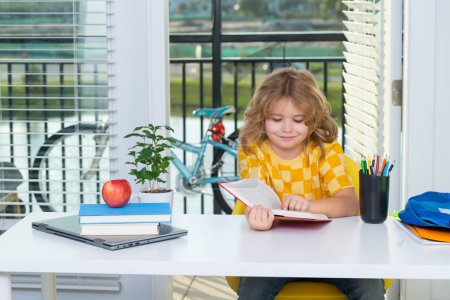Photo for School kid reading book. Smart caucasian school boy kid pupil student going back to school. Little student kid preparing school homework. Child involved in doing task, studying homeschooling - Royalty Free Image