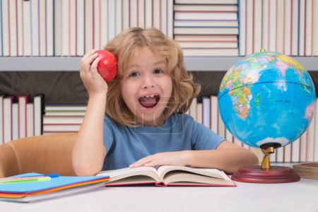 Photo for School boy with books and apple in library. Nerd pupil. Clever child from elementary school with book. Smart genius intelligence kid ready to learn - Royalty Free Image