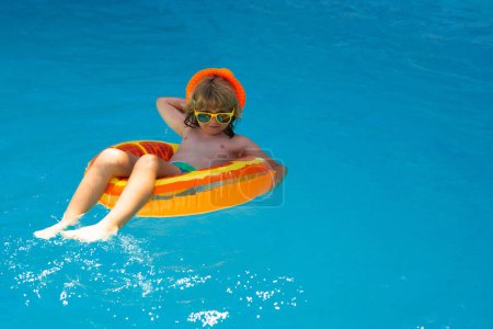Téléchargez les photos : Petit garçon se relaxant dans la piscine. Enfant nageant dans la piscine d'eau. Activité estivale pour enfants, sports nautiques. Vacances d'été avec enfants - en image libre de droit