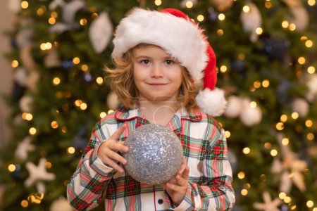 Foto de Niño en sombrero de santa cerca del árbol de Navidad en casa - Imagen libre de derechos