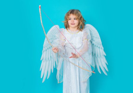 Photo for Angel child shoots a love arrow from a bow on Valentines Day. Child at angel costume. Kid with angel wings. Isolated studio shot - Royalty Free Image