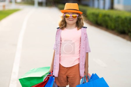 Foto de Un chico con bolsas de compras. Moda y venta. Pequeño comprador cliente - Imagen libre de derechos