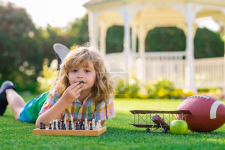 Photo for Chess game for kids. Child playing chess outdoor in park. Kid playing chess and having fun outdoor on backyard or summer park - Royalty Free Image
