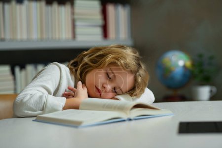 Foto de Niño de escuela cansado, alumno aburrido durmiendo en la escuela. Educación para niños y concepto escolar. Retrato del alumno escolar durmiendo en el libro en la biblioteca - Imagen libre de derechos