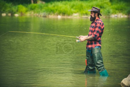 Foto de Joven pescando. Pescador con caña, carrete giratorio en la orilla del río. Hombre la captura de peces, tirando de la caña mientras pesca en el lago. Naturaleza salvaje. El concepto de escapada rural - Imagen libre de derechos
