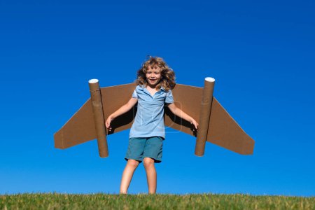 Photo for Kid imagination, child pilot with paper wings having fun at outdoor. Summer vacation and travel concept. Boy with toy jetpack dreaming of piloting. Success, leader and winner concept - Royalty Free Image