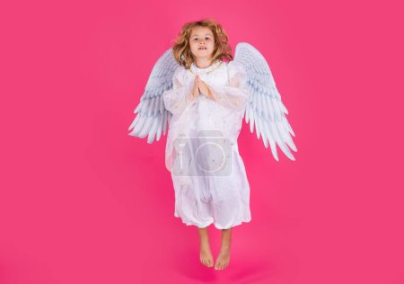 Téléchargez les photos : Little angel jump, kids jumping, full body. Little angel fly. Valentine angel. Little cupid child. Kid angel with angels wings, isolated on pink studio background. Valentines day gift card - en image libre de droit