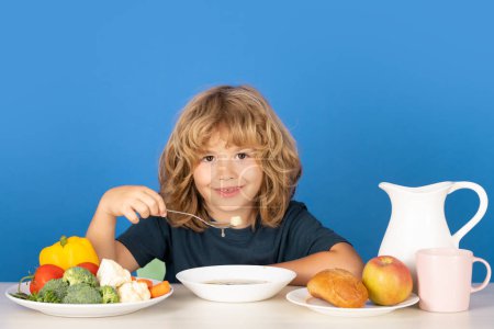Photo for Child eating soup. Child eating healthy food at kithen. Baby eat soup with spoon - Royalty Free Image