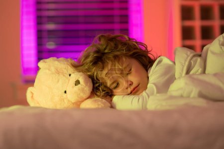 Photo for Kid enjoying sweet dreams. Kid sleeping with a toy teddy bear in bed. Child sleeping in bed under blanket. Kid lying on pillow, child rest asleep, enjoy healthy sleep or nap - Royalty Free Image