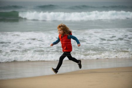 Téléchargez les photos : Sporty kid running in nature. Child run at seaside. Kids running on beach. Summer vacation. Happy kid boy playing on beach. Happy childhood - en image libre de droit