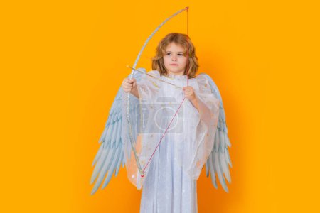 Téléchargez les photos : Kid cupid hold bow and arrow. Christmas kids. Little cupid angel child with wings. Studio portrait of angelic kid - en image libre de droit