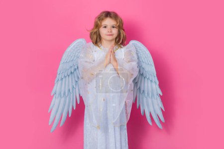 Foto de Angel prayer. Little cupid child. Kid angel with angels wings, isolated on pink studio background. Valentines day gift card - Imagen libre de derechos