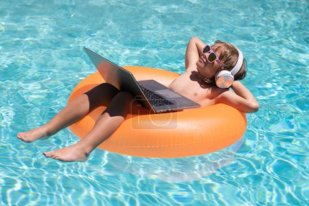 Photo for Funny little businessman freelancer relaxing in the pool, using laptop computer in summer water. Child online working on tropical sea - Royalty Free Image