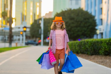 Foto de Discounts and sales. Happy kid boy with shopping bags. Little child on shopping. Trends and brands. Summer sale - Imagen libre de derechos