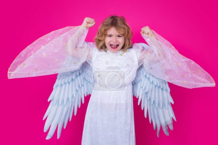 Téléchargez les photos : Enfant en costume d'ange robe blanche et ailes de plumes. Enfant innocent. Petit ange sur fond de studio isolé - en image libre de droit