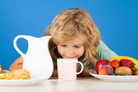 Photo for Children eat breakfast. Kid with dairy milk. Kid boy pouring whole cows milk. Healthy breakfast for kids. Portrait of child eat fresh healthy food in studio - Royalty Free Image