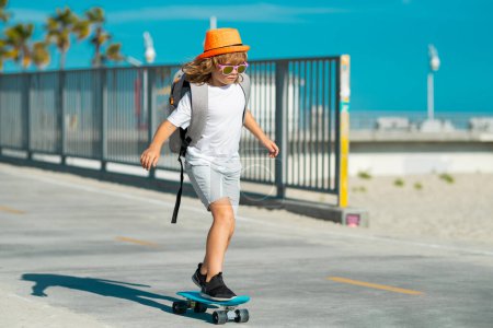 Foto de Kid with skateboard. Child hold skate board. Healthy sport and activity for school kids in summer. Summer sports fun. Kid skating on skateboard - Imagen libre de derechos
