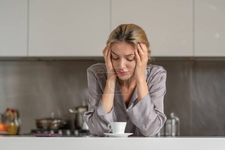 Foto de Bored depressed woman in the kitchen in the morning - Imagen libre de derechos