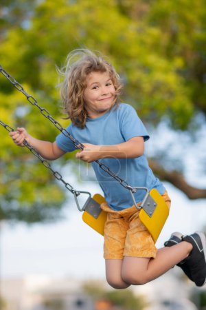 Téléchargez les photos : Child boy on swing. Kid swinging on playground. Cute excited amazed child on swing. Cute child swinging on a swing. Crazy playful child swinging very high - en image libre de droit