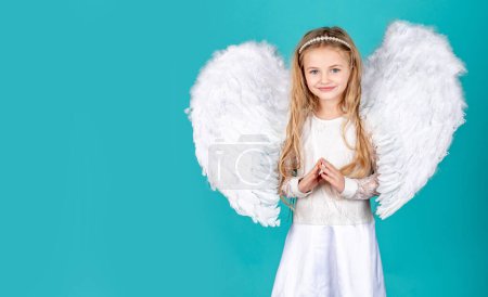 Foto de Angel child banner, isolated studio background. Cute child girl in white dress standing over color background. Child angel with a beautiful wings. Happy little Angel - Imagen libre de derechos