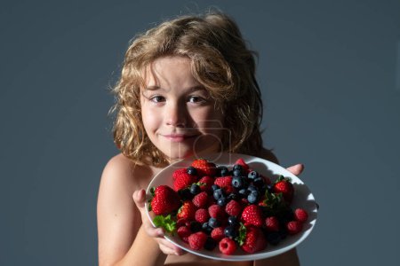 Photo for Healthy food. Child boy hold plate of mix summer fruits. Healthy organic strawberry fruit, summer season - Royalty Free Image